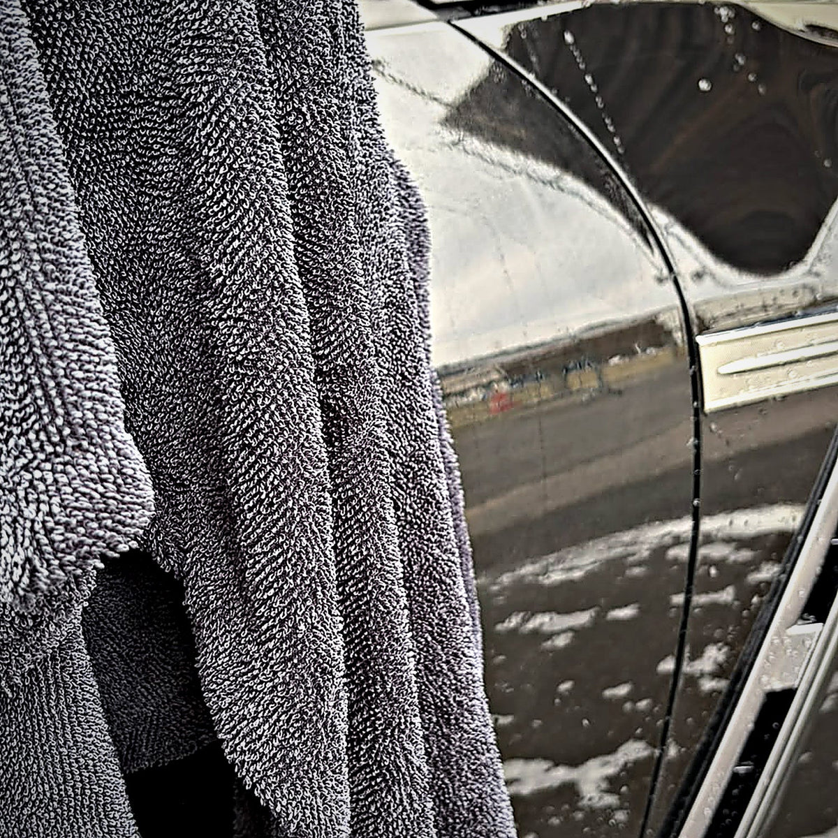 Serviette de séchage MIRE 60 × 90 cm suspendue sur le flanc mouillé d'une Nissan GT-R noire