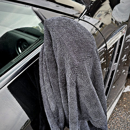Serviette microfibre MIRE sur le flanc d'une voiture noire, près du rétroviseur