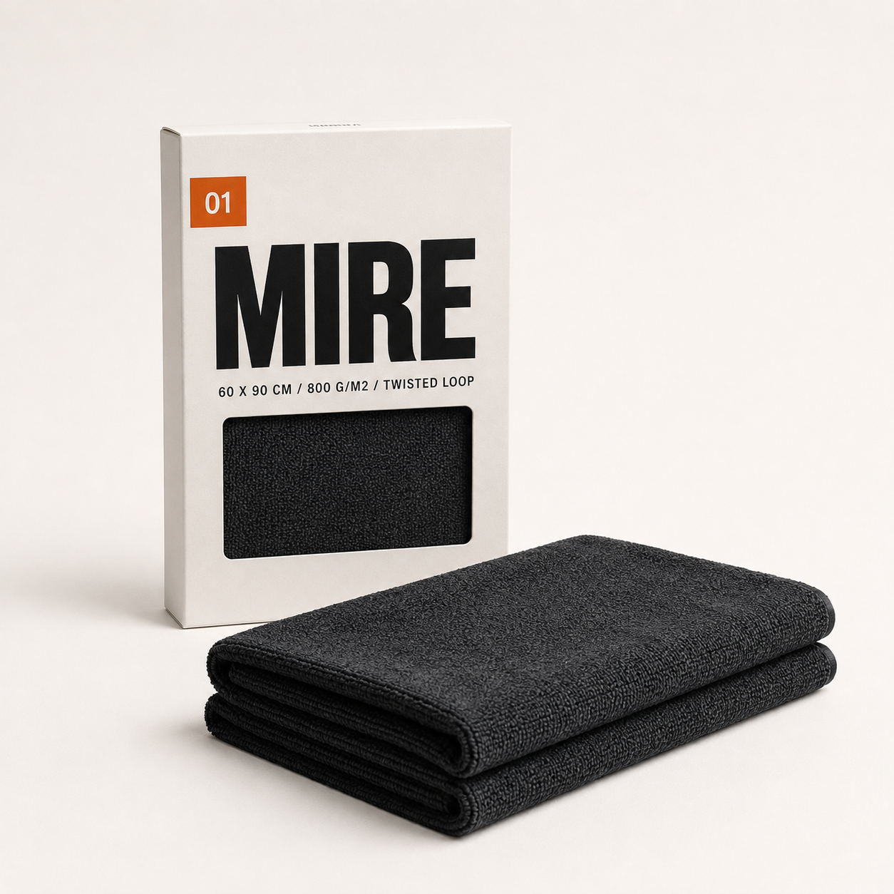 Serviette de séchage MIRE 01 pliée devant son étui carton, packshot studio