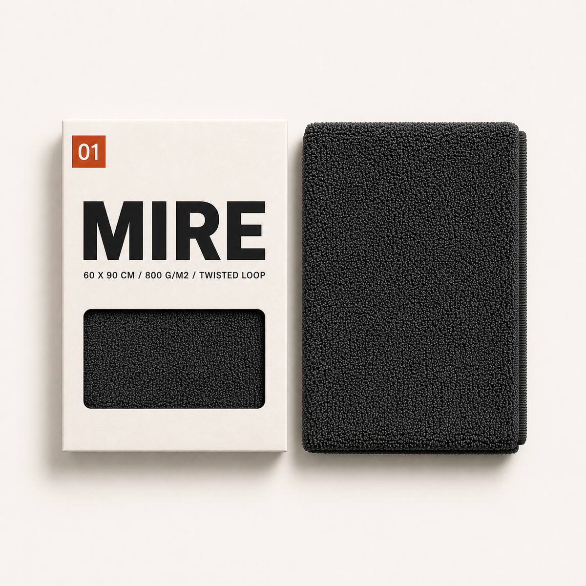 Étui carton MIRE 01 et serviette microfibre anthracite pliée, côte à côte sur fond crème